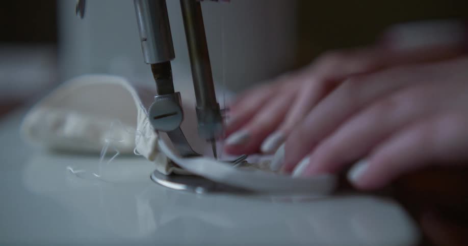 A woman feeding white fabric through a sewing machine