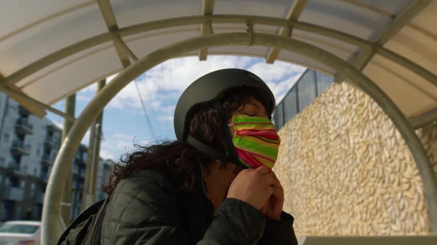 A woman wears her bicycle helmet and fastens it