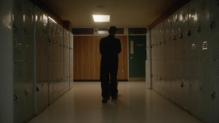 A janitor walking down a hallway with a mop and bucket
