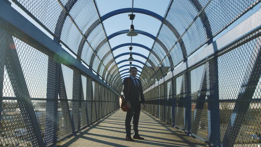 A man is standing on a pedestrian bridge