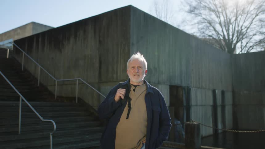 A man is posing outside by a stairwell