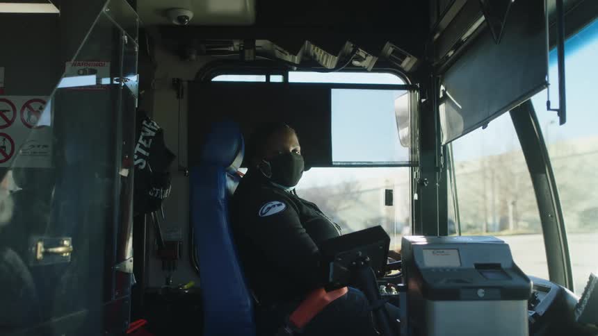 A female bus driver turns her head toward the open bus door