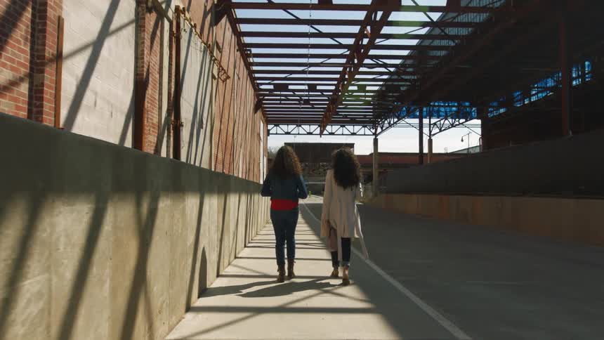 Two women walk past building with raised floor and loading doors