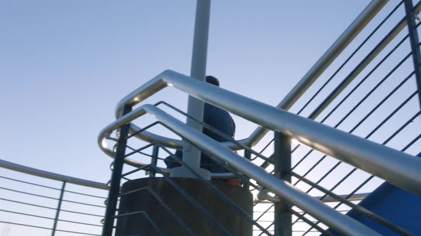 A man in a business suit is walking down outdoor stairs as the sun shines brightly