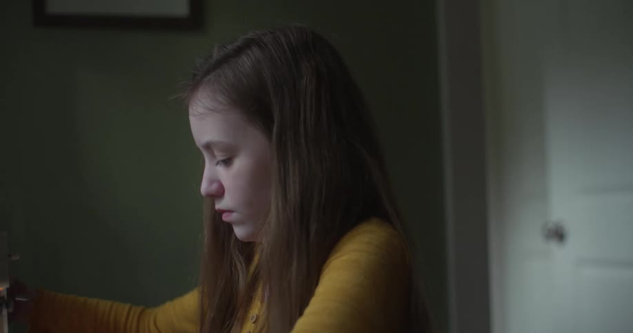 Girl sits in room adjusting machine while crafting