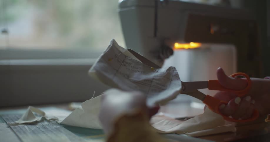 A person is using scissors to cut out fabric with a pattern