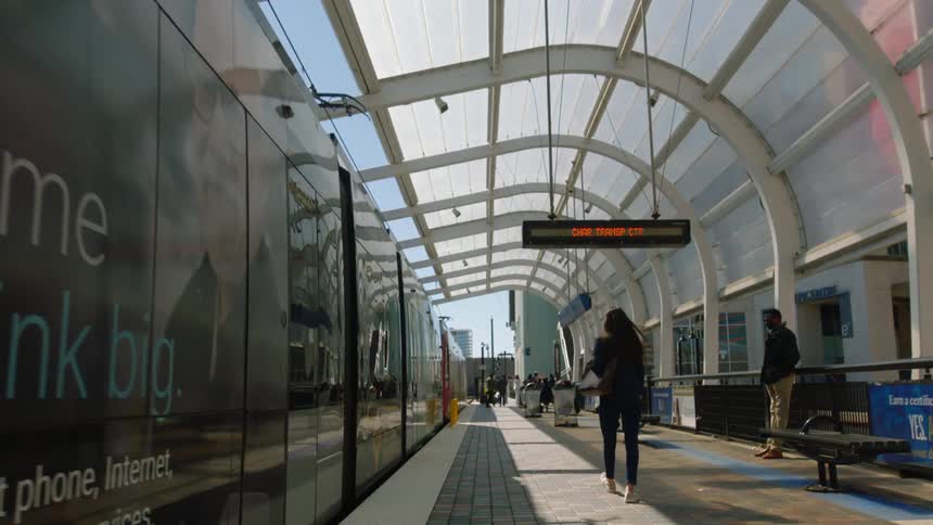 A woman looks to her right then walks off to her left when getting off a train