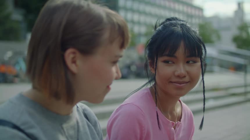 Two girls smile while sitting outside