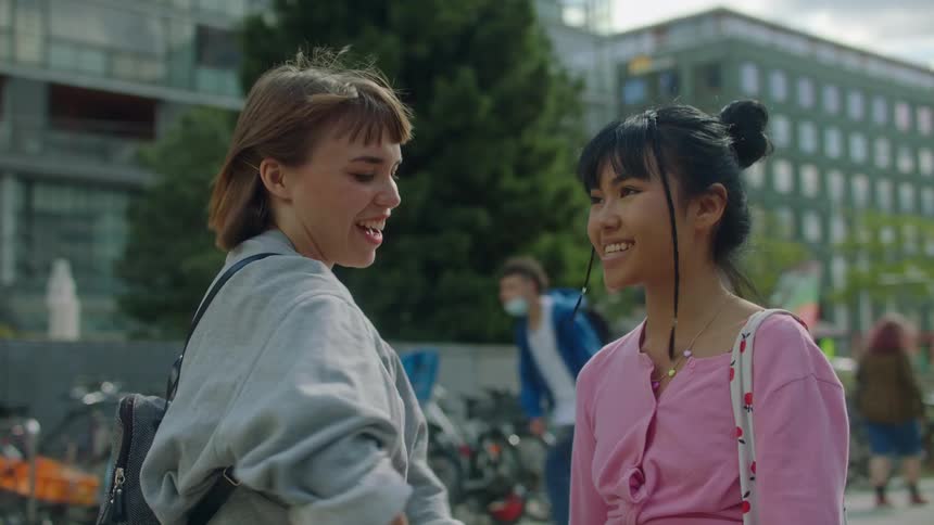 One girl surprising another girl before hugging and talking