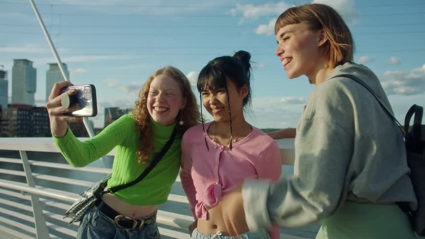 Three women pose while taking a selfie