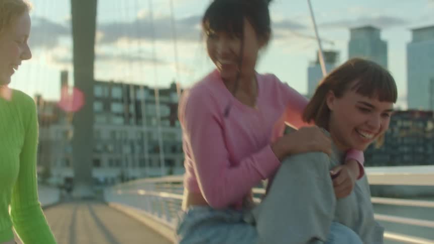 Three women jump around playing as they cross the bridge