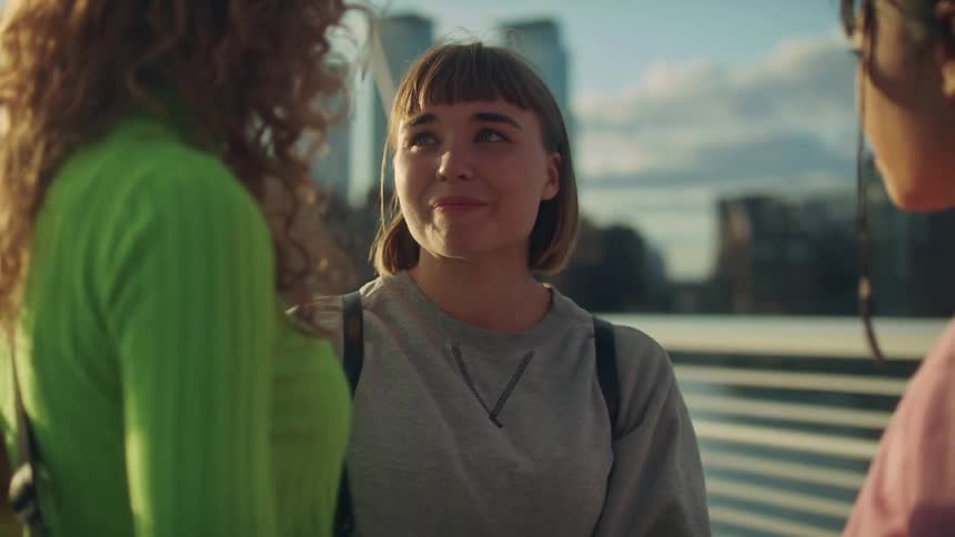 Three teenage girls hugging and saying goodbye on a city bridge