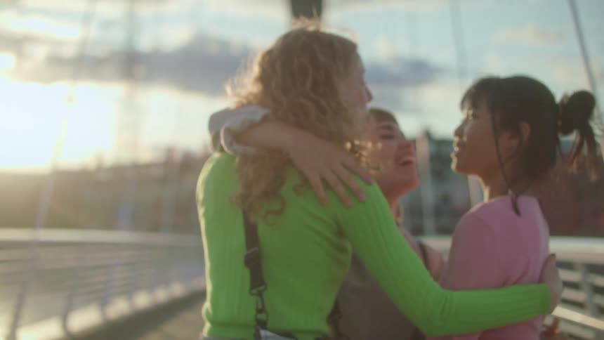 Women walk toward each other on a bridge and embrace