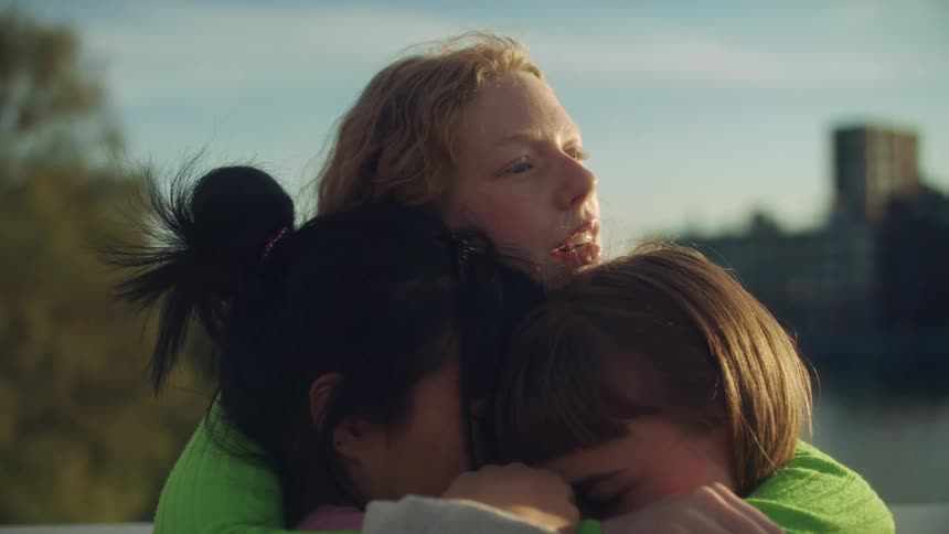 Three teen girls hugging and saying goodbye outside in the daytime