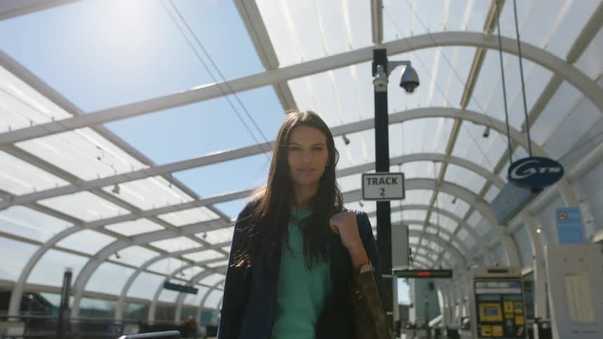 A woman smiling while standing at a bus stop in a city