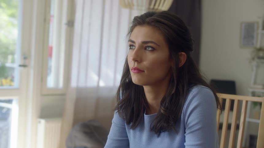 A woman rolls her eyes while sitting in her kitchen chair