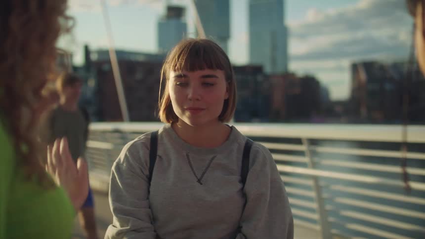 Three teenage girls hugging and saying goodbye on a city bridge