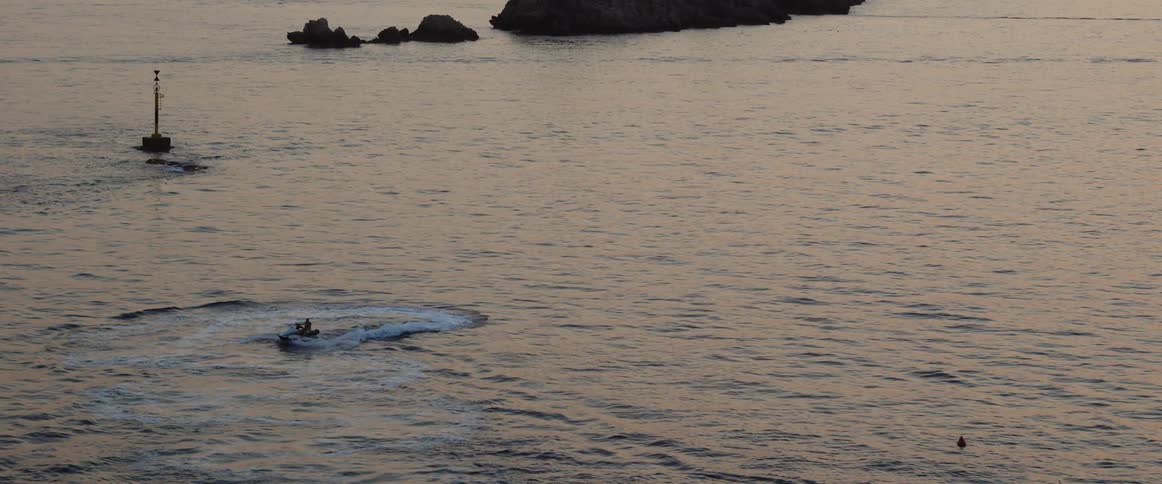 A person rides a jet ski on the ocean in the evening
