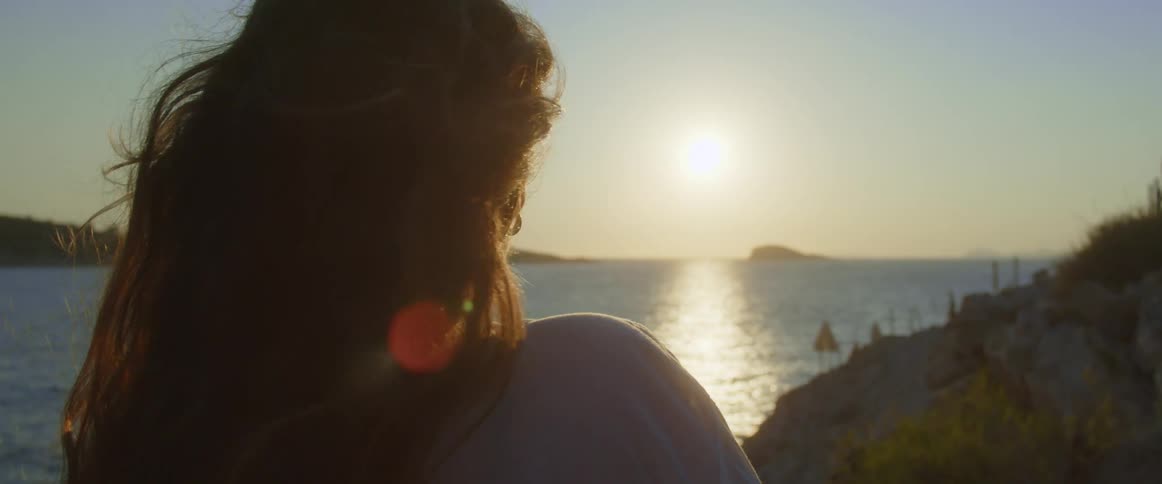 A woman looks out over the ocean while standing on the coast during the day
