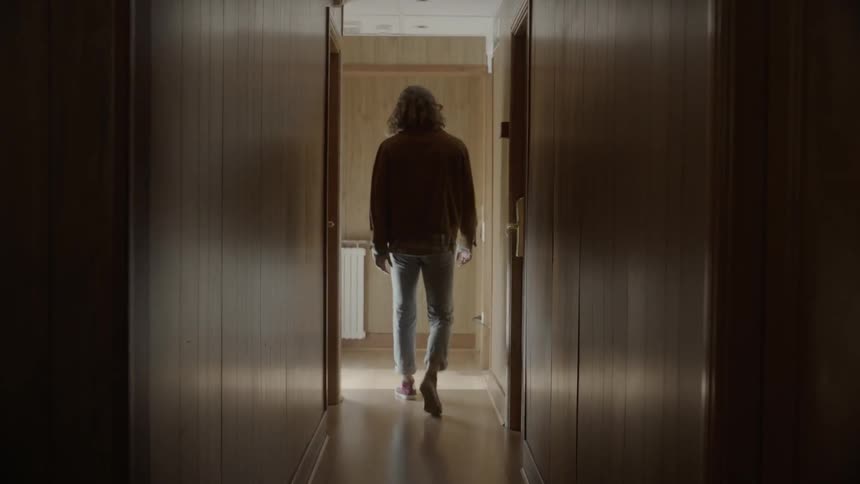 A man walks down a dark hallway