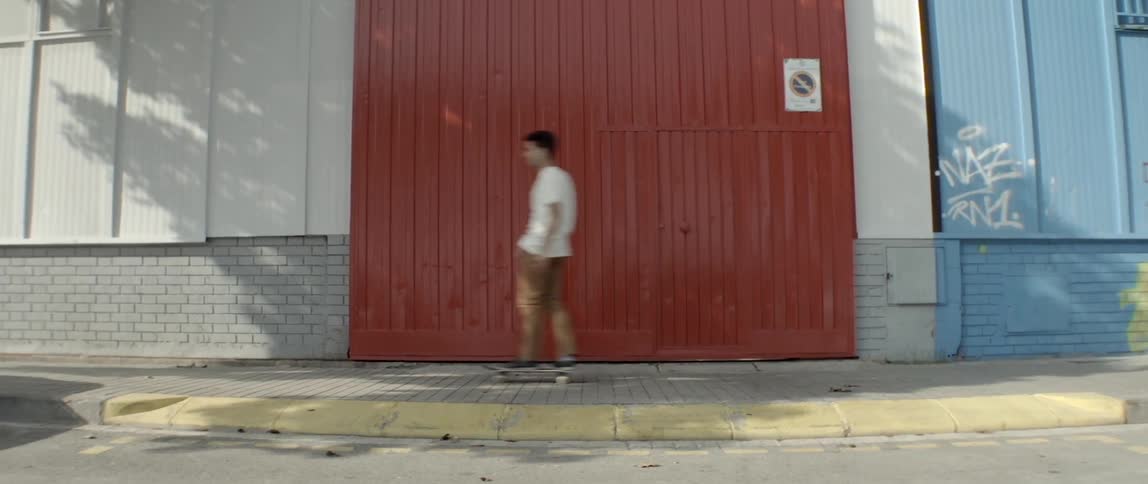 A skateboarder rides past a large red door