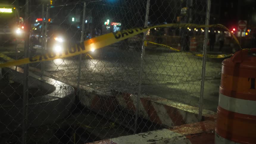 Cars driving near a construction site on the street in the city at night