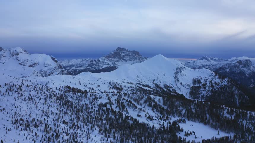 A snow covered mountain range with the sky and clouds in the background