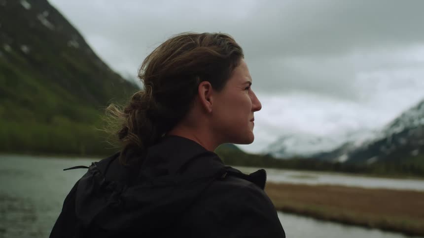 A woman is standing by a lakeside mountain