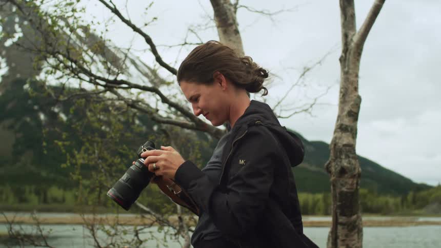 A woman is using a long lens to photograph the mountains