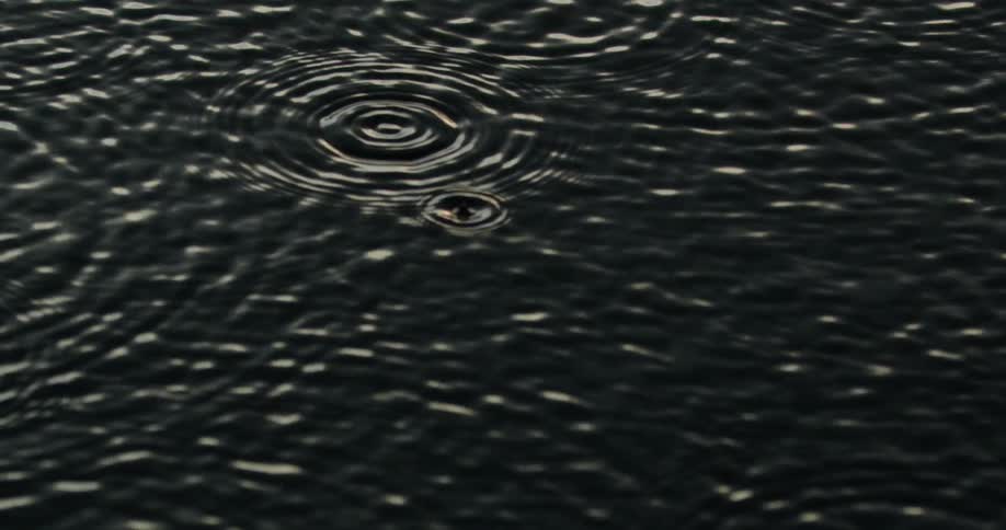 Raindrops are falling into water and causing ripples