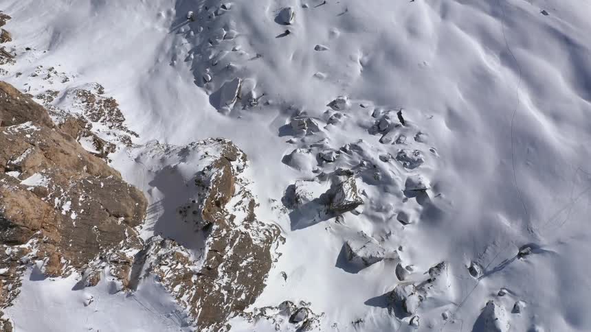 View looking down a steep snow covered mountain side