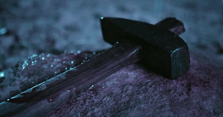 Rain falls on an ax that is laying on a stone