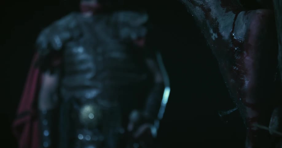 A man in armor looks at a man who is bleeding