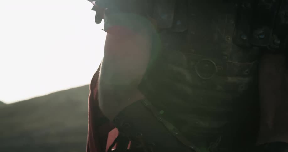 Roman legionnaire wearing armor tightens strap standing next to hill