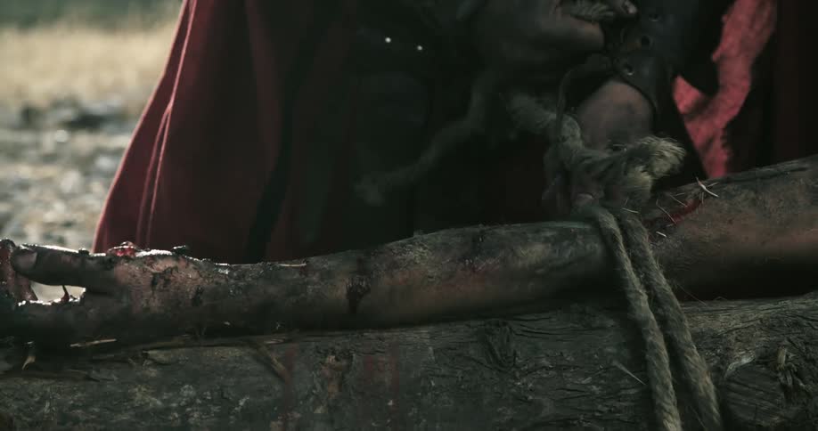 A person is being tied to wood with rope