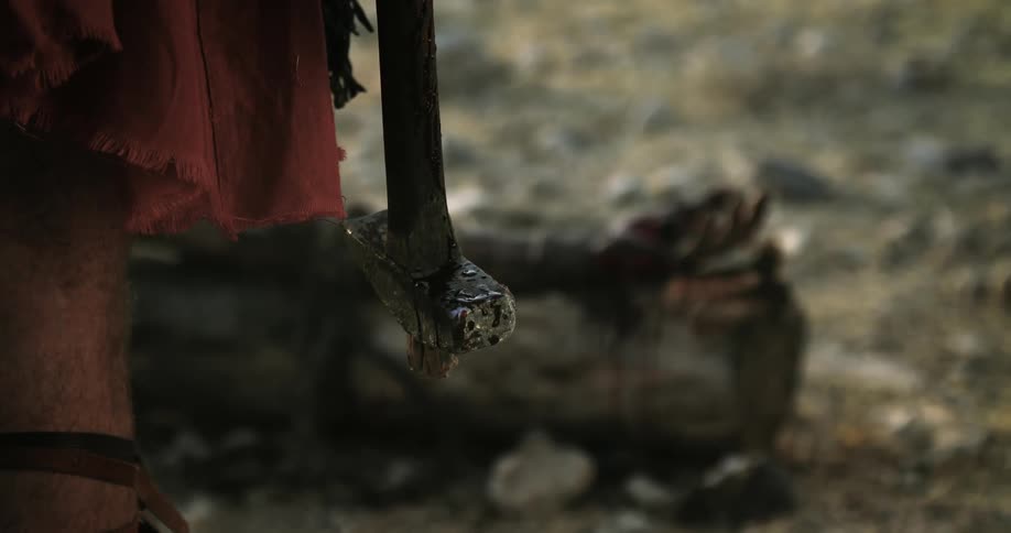 A roman soldier holding a hammer with jesus nailed to the cross