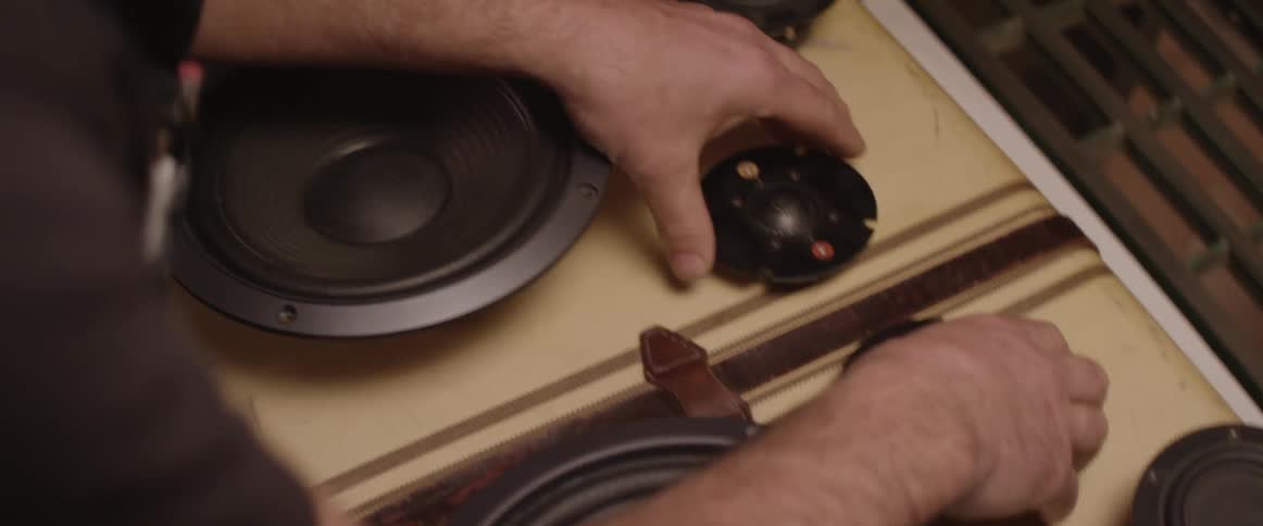 A person places speakers on a suitcase