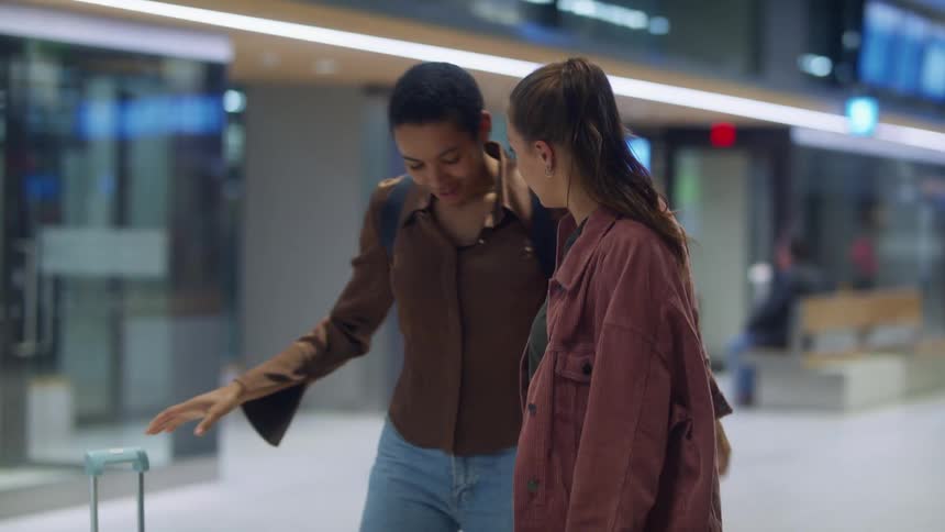 Two women hug at an airport and they start walking together