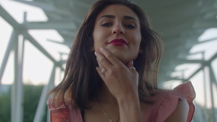 A model caresses her face as she poses on a pedestrian bridge