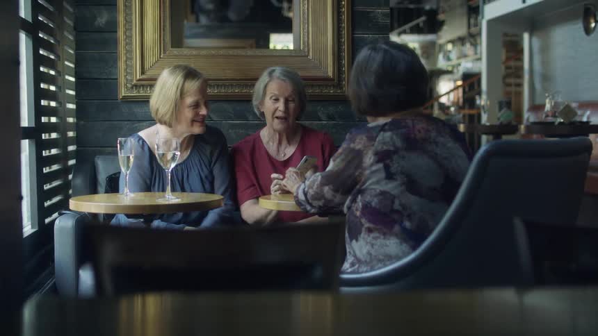 Three women talk together with drinks