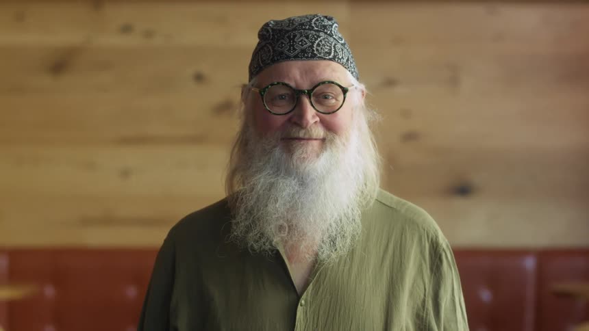 A man with a long white beard is smiling