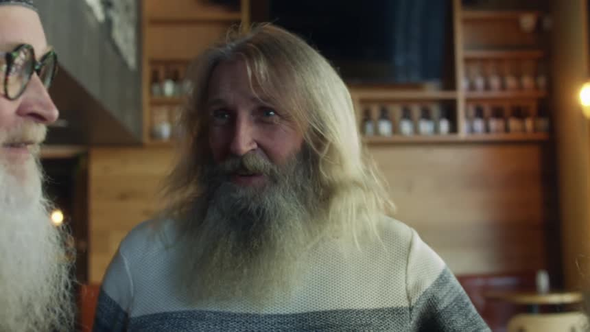 Elderly men with long beard and hair talk with each other in pub