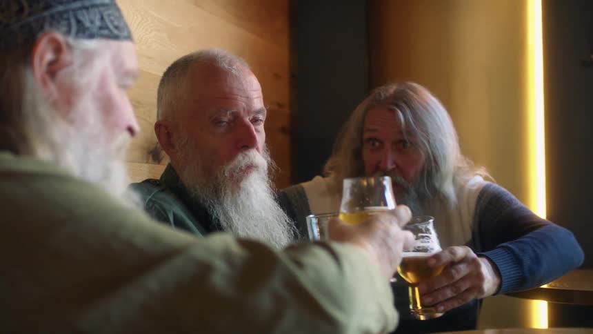 Group of men with white beards toasting and drinking beer in a bar