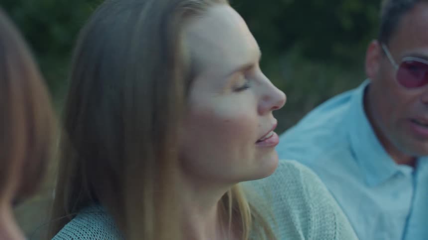 Blonde woman with blue eyes sitting with friends talking outdoorstion