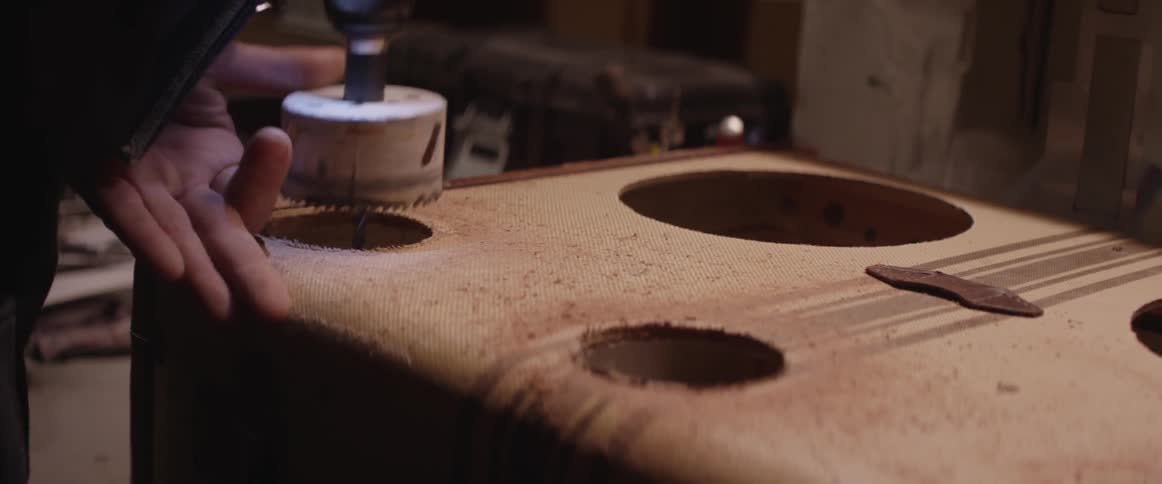 A person drills holes into a suitcase