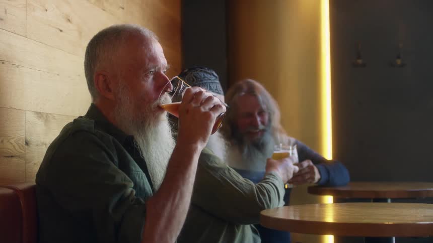 Three long bearded men drink beer while sitting in a restaurant booth