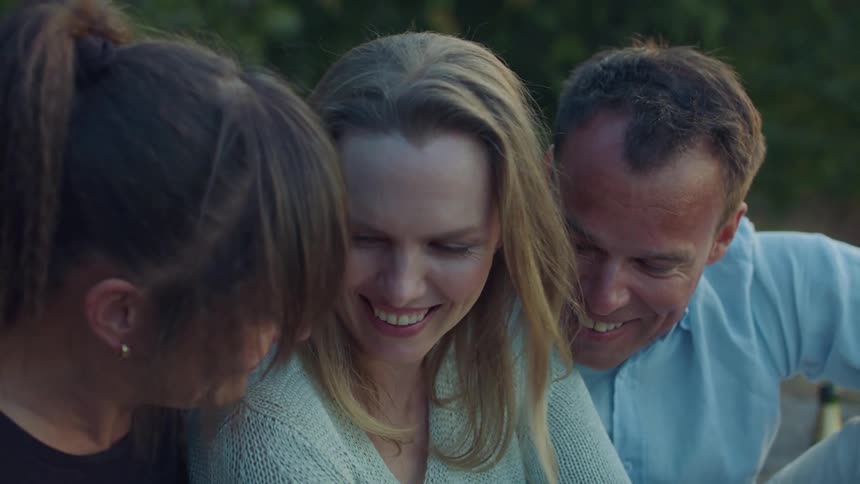 Three people smile and talk together outside