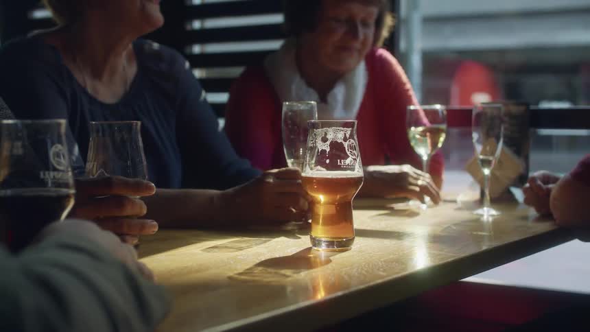 A group of friends are seated at a table in a diner having alcoholic beverages and conversation in the daytime