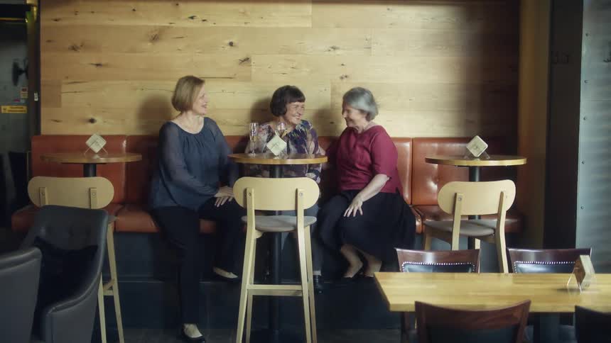 Three women sit down in a restaurant with some drinks
