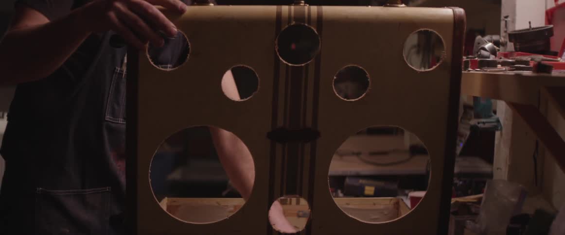 A man opens a suitcase that he's cut holes into